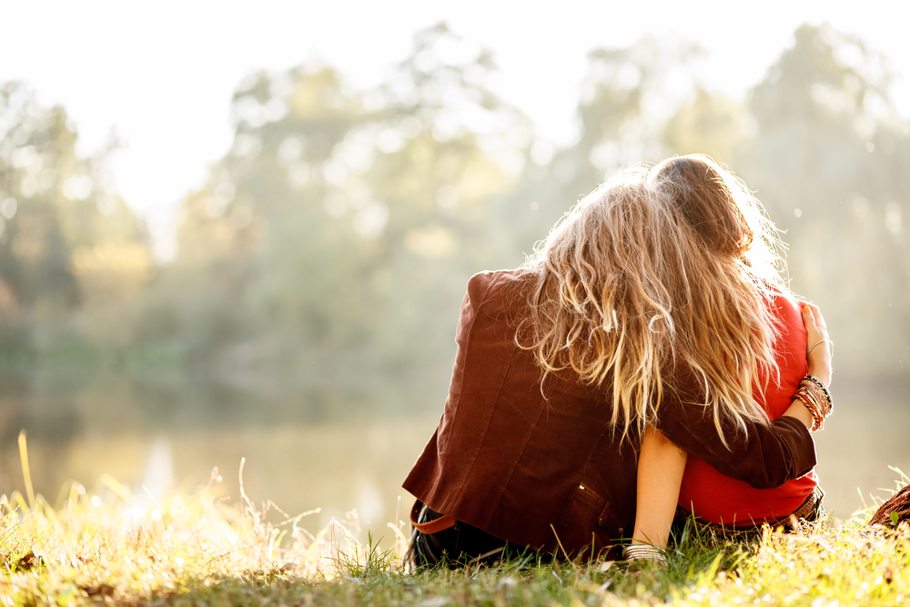 Two girls embracing by lake